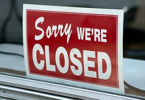 closeup of a 'sorry we're closed' sign in a shop window